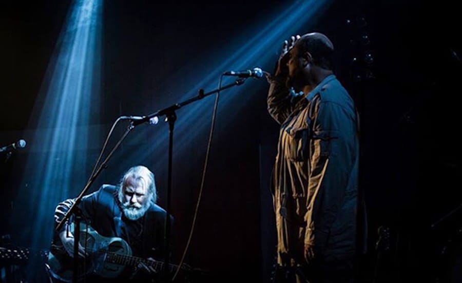 Dramatic musical performance with guitar and microphone.